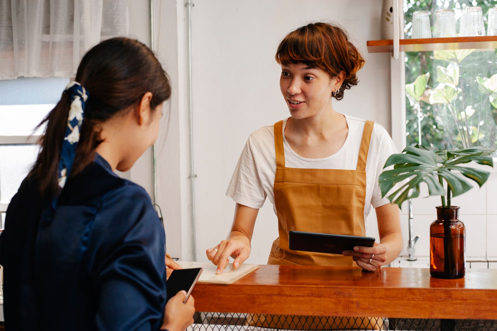 Two restaurant employees coordinating together around a tablet